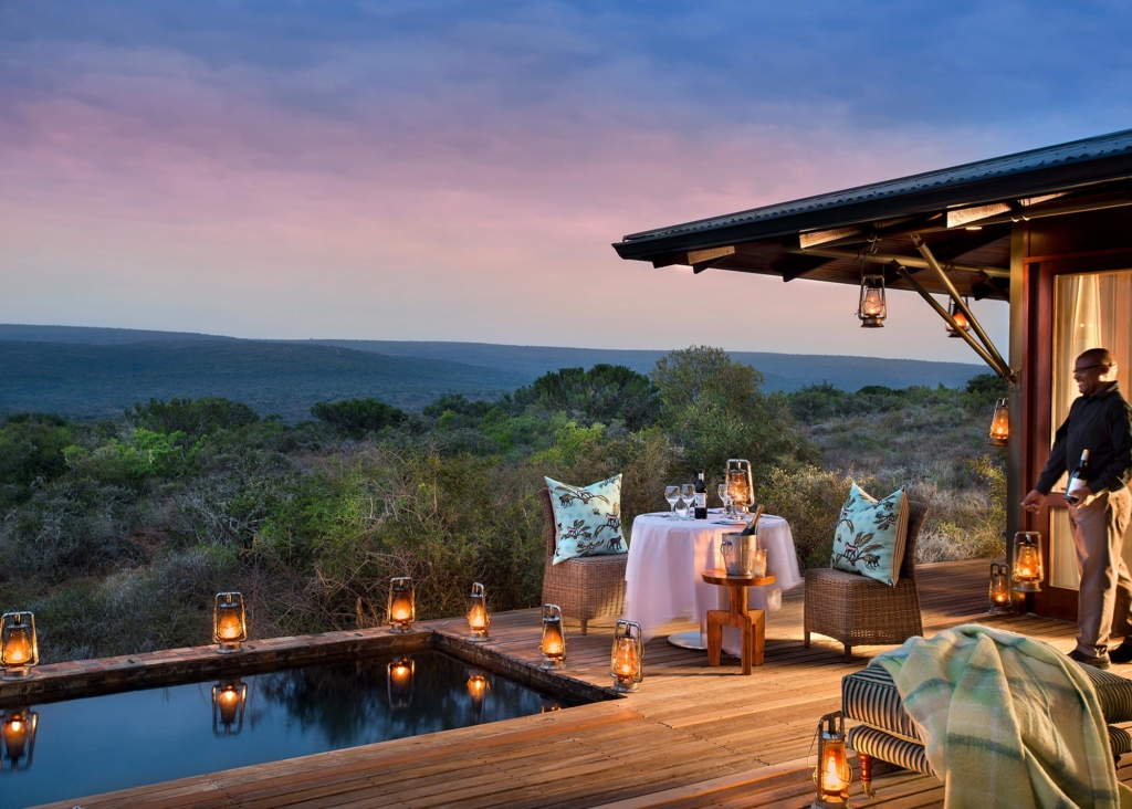 An elegantly set dining area beside a private pool with scenic views at dusk.