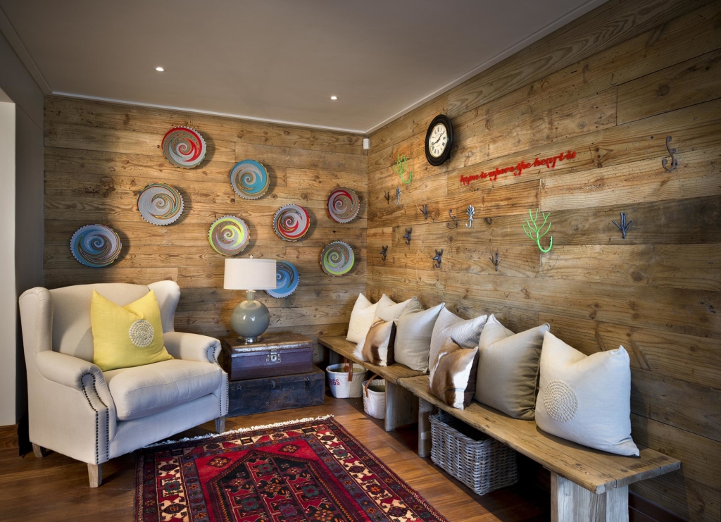 A cozy living room with wooden walls, decorative art, a clock, and comfortable seating.