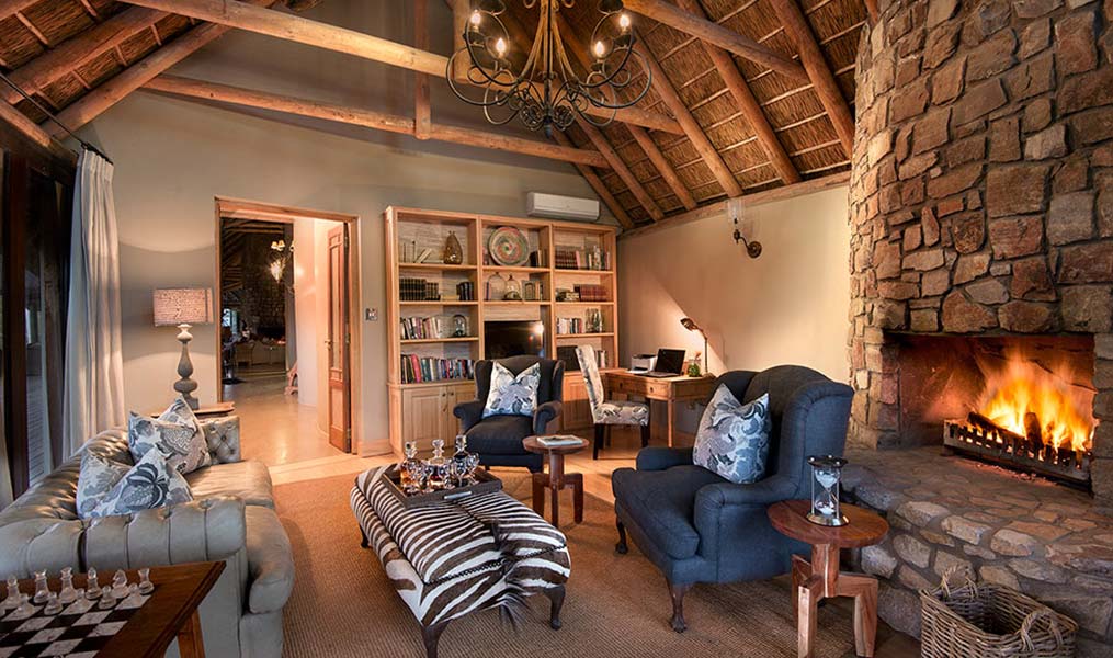 A cozy living room with a stone fireplace, comfortable seating, and a bookshelf.