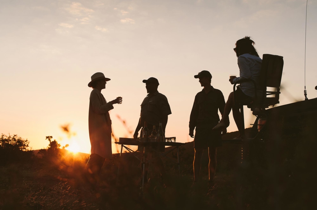 Silhouetted figures converse against a sunset backdrop.