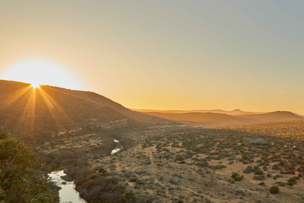 A scenic landscape at sunset with mountains and a river.