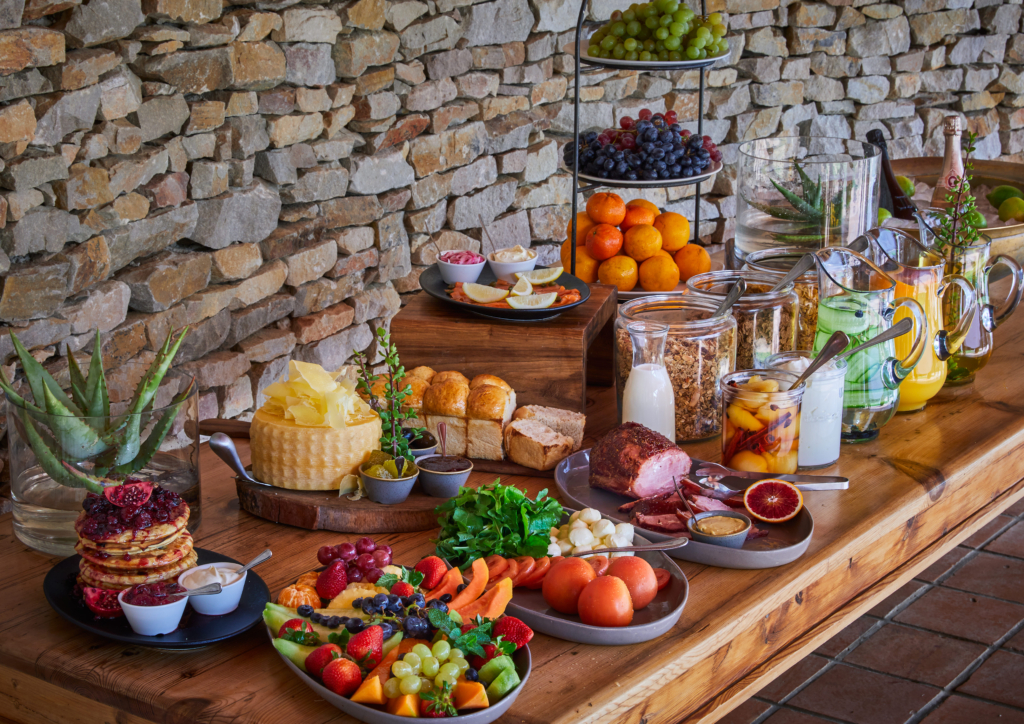 A vibrant display of a variety of fresh fruits, snacks, and beverages on a wooden table.