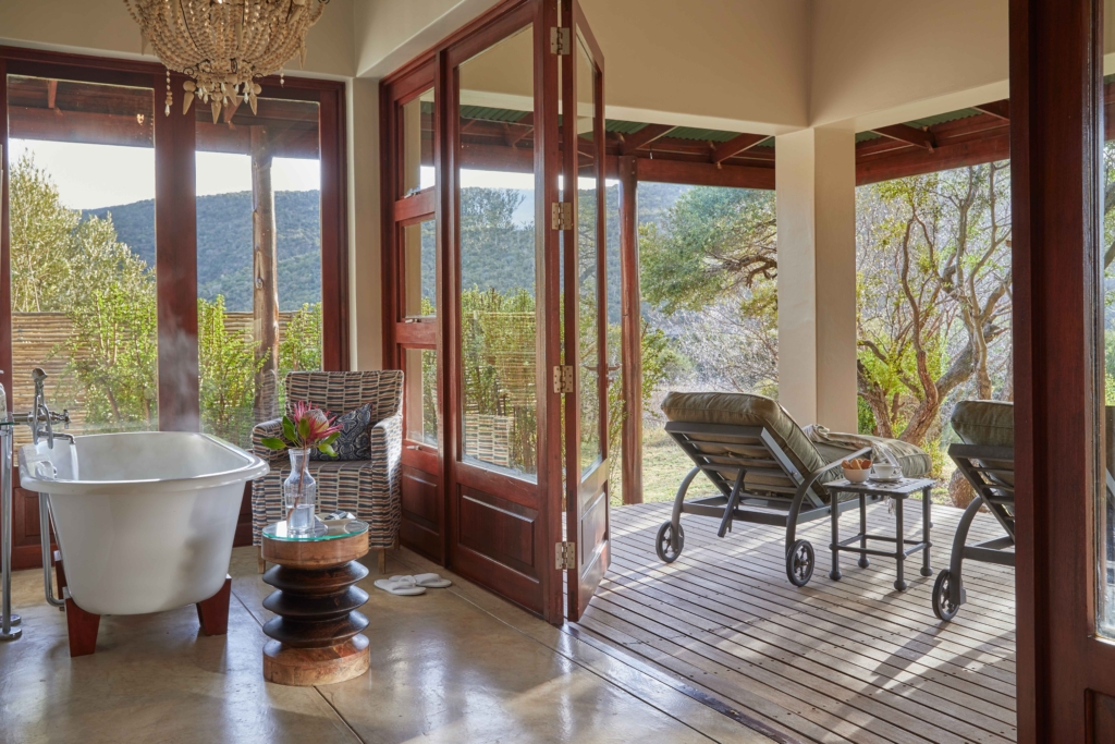 A stylish bathroom with a freestanding tub opens to a patio with a view of nature.
