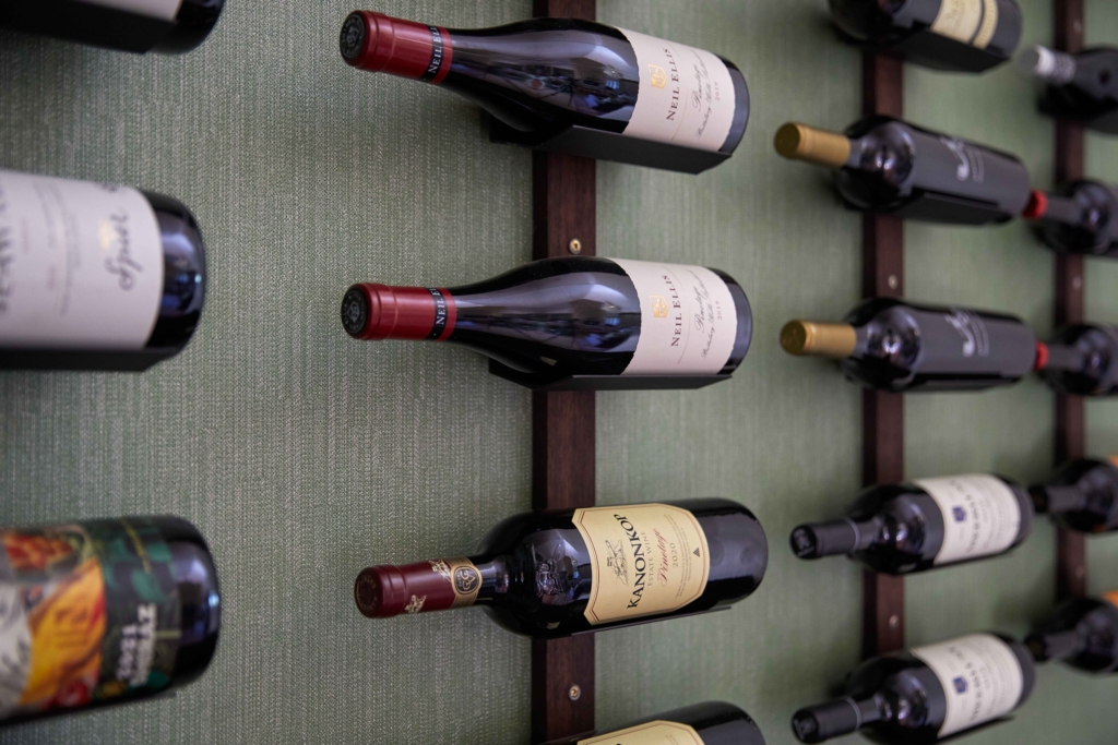 A display of various wine bottles on a wall-mounted rack.