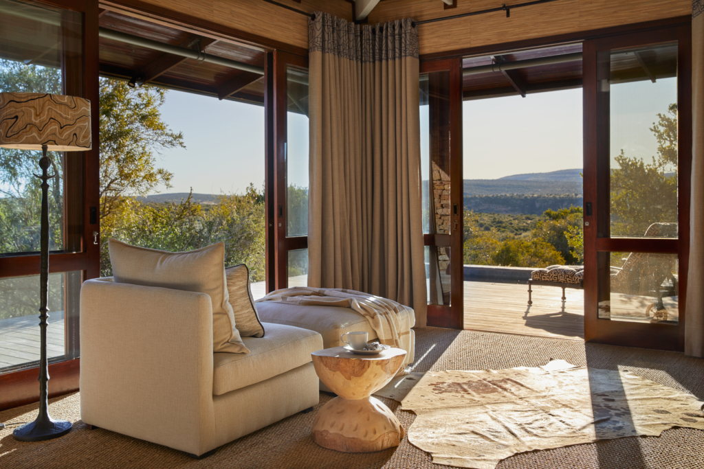 A modern living room with large windows offering a view of nature.