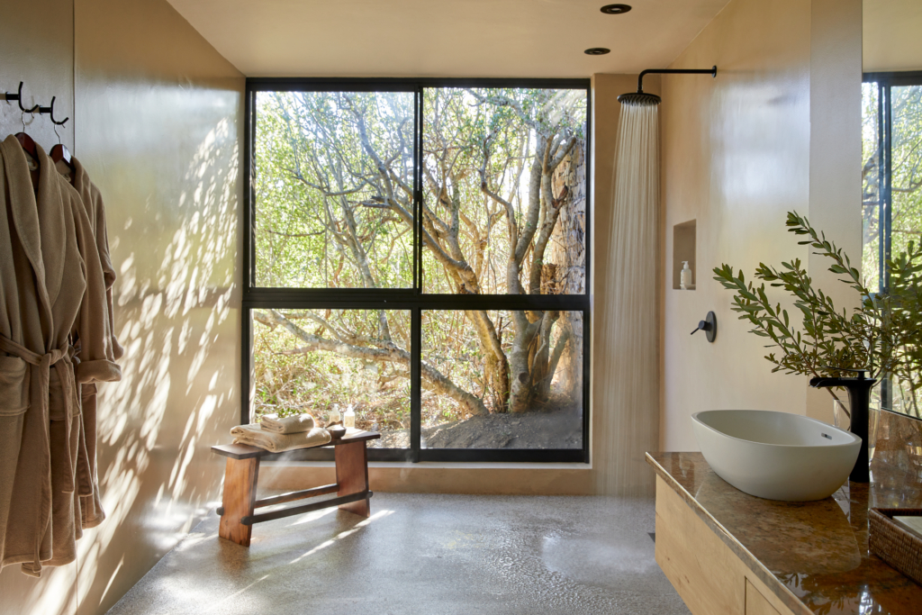 A modern bathroom featuring a window with a view of a tree, a shower, and minimalist decor.