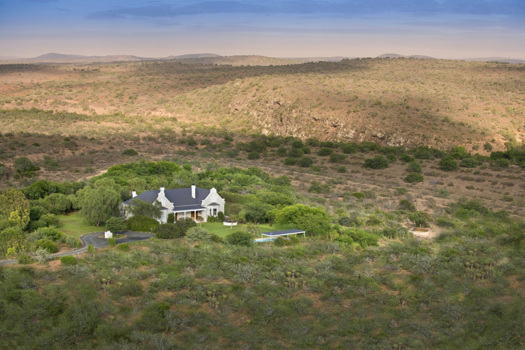 A secluded house surrounded by lush greenery in a vast landscape.